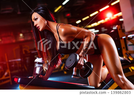 Young sports woman posing in gym with dumbbells, tattoo on body 139862803