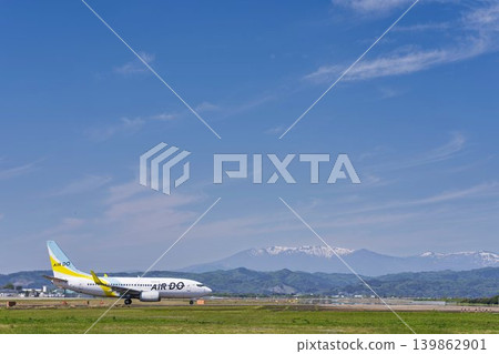 Sendai Airport on a sunny day: Zao mountain range and a taxiing airplane. Natori City, Miyagi Prefecture. 139862901