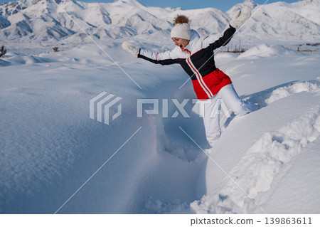 Young woman tourist falling in deep snow at winter mountains background Young woman tourist falling in deep snow at winter mountains background 139863611
