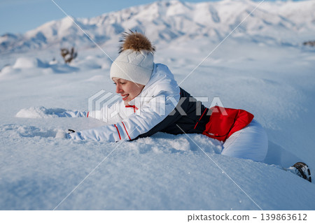 Young woman tourist fell in deep snow on mountains background 139863612
