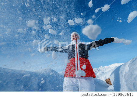 Young happy woman throw snow on winter mountains background Young happy woman throw snow on winter mountains background 139863615