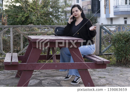 Woman Talking on Phone in the Park. Woman Talking on Phone in the Park. 139863659
