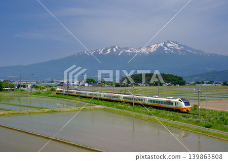 The limited express train "Inaho" runs with Mount Chokai in the background during springtime. The limited express train "Inaho" runs with Mount Chokai in the background during springtime. 139863808