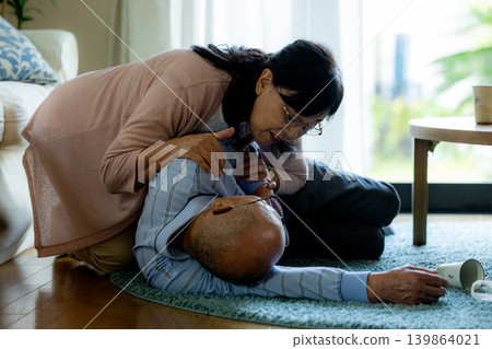 A senior man who has collapsed and a senior woman providing first aid. A senior man who has collapsed and a senior woman providing first aid. 139864021