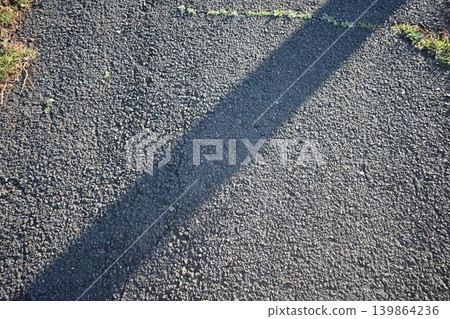 Abstract background of an asphalt road with the light and shadows of early morning falling. Abstract background of an asphalt road with the light and shadows of early morning falling. 139864236