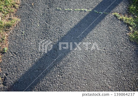 Abstract background of an asphalt road with the light and shadows of early morning falling. Abstract background of an asphalt road with the light and shadows of early morning falling. 139864237