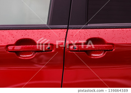 The door and door handle of a red car, wet from the rain. The door and door handle of a red car, wet from the rain. 139864389