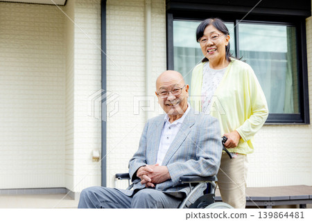 Wife supporting elderly person in wheelchair Wife supporting elderly person in wheelchair 139864481