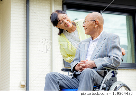Wife supporting elderly person in wheelchair 139864483