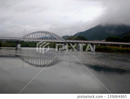 The scenery of the white arch bridge reflected on the river surface under a rainy sky. The scenery of the white arch bridge reflected on the river surface under a rainy sky. 139864865