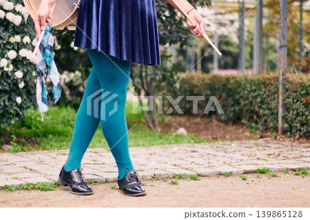 View of legs wearing green tights and a woman's skirt, belonging to a chinchinera, a female street musician who dances and plays her drum in the streets. Chilean heritage, Chilean culture View of legs wearing green tights and a woman's skirt, belonging to a chinchinera, a female street musician who dances and plays her drum in the streets. Chilean heritage, Chilean culture 139865128
