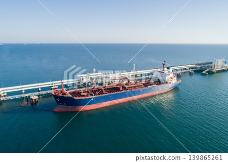 Aerial view of a large oil tanker docked at a pier in the port in process of loading. Aerial view of a large oil tanker docked at a pier in the port in process of loading. 139865261
