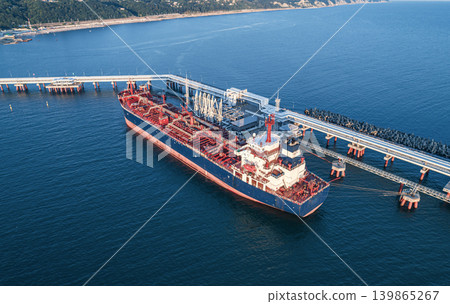 Aerial view of a large oil tanker docked at a pier in the port in process of loading. Aerial view of a large oil tanker docked at a pier in the port in process of loading. 139865267