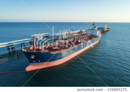 Aerial view of a large oil tanker docked at a pier in the port in process of loading. Aerial view of a large oil tanker docked at a pier in the port in process of loading. 139865275