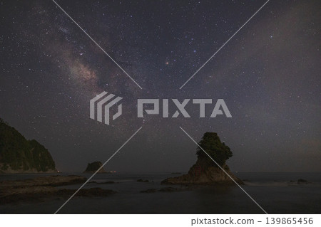 A starscape photograph of a coastline with the Milky Way galaxy and an island with a torii gate shining brightly. A starscape photograph of a coastline with the Milky Way galaxy and an island with a torii gate shining brightly. 139865456
