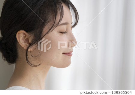 一位年輕女子閉著眼睛,面帶微笑;側臉。 一位年輕女子閉著眼睛,面帶微笑;側臉。 139865504