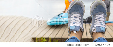 A banner with a copy of the space on the left. Women's legs in blue jeans and sneakers, against the background of sports people, first-person shooting A banner with a copy of the space on the left. Women's legs in blue jeans and sneakers, against the background of sports people, first-person shooting 139865896