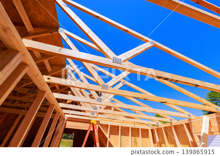 Workers are building wooden roof truss frame with beams supports on construction site Workers are building wooden roof truss frame with beams supports on construction site 139865915