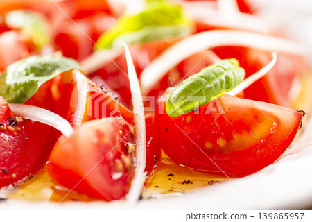 A refreshing salad of red tomatoes and basil, garnished with olive oil, as an appetizer. A refreshing salad of red tomatoes and basil, garnished with olive oil, as an appetizer. 139865957