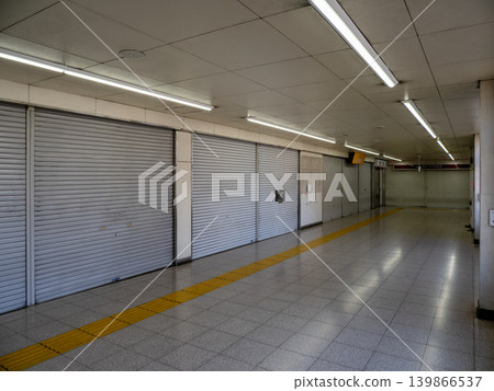A station concourse with its shutters closed; an empty passageway and a quiet morning scene. A station concourse with its shutters closed; an empty passageway and a quiet morning scene. 139866537