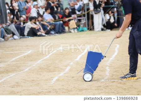 Teacher drawing lines at sports day Teacher drawing lines at sports day 139866928