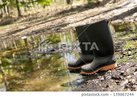 Black gum boots are at the puddle and mud in the yard in spring. Black gum boots are at the puddle and mud in the yard in spring. 139867244