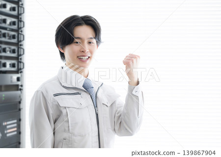 一位年輕工程師在資料中心的音響設備前微笑,象徵著他在維護和維修工作中的成長。 一位年輕工程師在資料中心的音響設備前微笑,象徵著他在維護和維修工作中的成長。 139867904