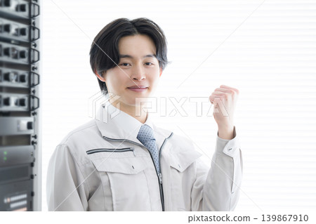 A young engineer smiles in front of server equipment and sound systems for machinery, representing his growth in maintenance and repair work. A young engineer smiles in front of server equipment and sound systems for machinery, representing his growth in maintenance and repair work. 139867910