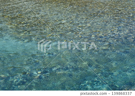 透過清澈湛藍的水面,可以看到河床上的石頭。 透過清澈湛藍的水面,可以看到河床上的石頭。 139868337