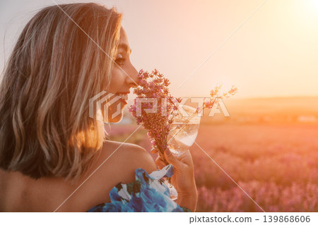 Woman lavender sunset enjoying an aromatic bouquet and refreshing drink in a blooming purple field during golden hour Woman lavender sunset enjoying an aromatic bouquet and refreshing drink in a blooming purple field during golden hour 139868606