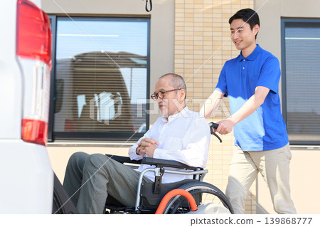 一名護理人員幫助坐在輪椅上的老人進入福利車輛。 139868777