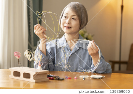一位老年婦女用水引繩製作髮飾 139869060