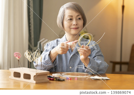 一位老年婦女用水引繩製作髮飾 139869074