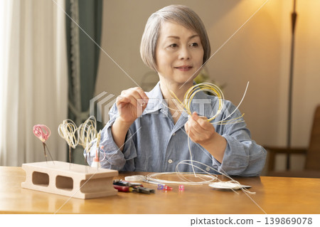 Senior woman making hair ornaments with mizuhiki (decorative cord) Senior woman making hair ornaments with mizuhiki (decorative cord) 139869078
