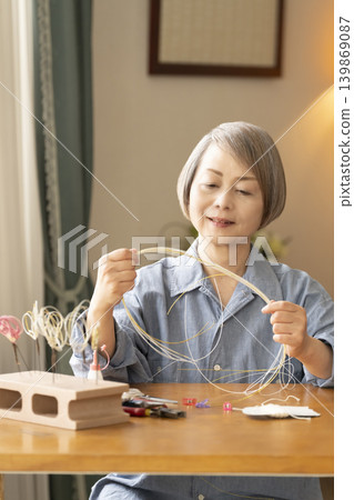 一位老年婦女用水引繩製作髮飾 139869087