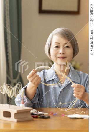 一位老年婦女用水引繩製作髮飾 139869089