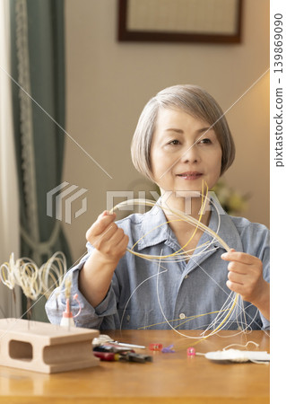 一位老年婦女用水引繩製作髮飾 139869090