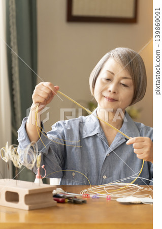 一位老年婦女用水引繩製作髮飾 139869091