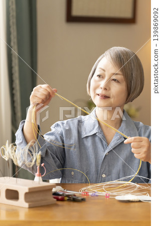 一位老年婦女用水引繩製作髮飾 139869092