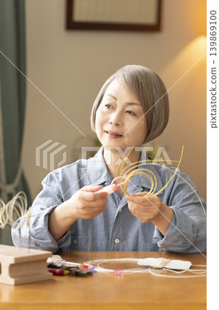 一位老年婦女用水引繩製作髮飾 139869100