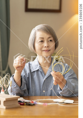 Senior woman making hair ornaments with mizuhiki (decorative cord) 139869106