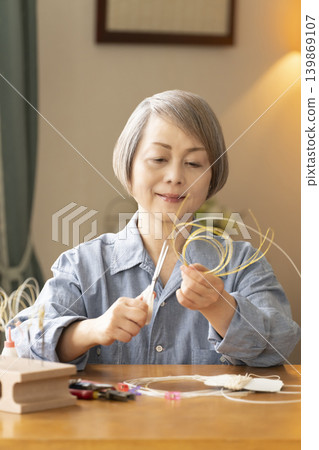 一位老年婦女用水引繩製作髮飾 139869107