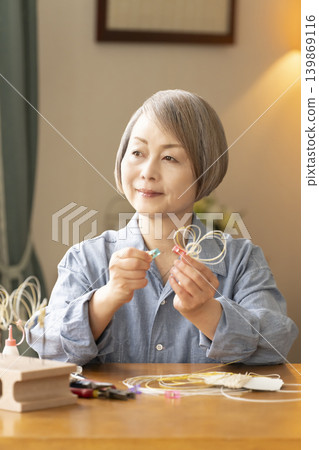 一位老年婦女用水引繩製作髮飾 139869116