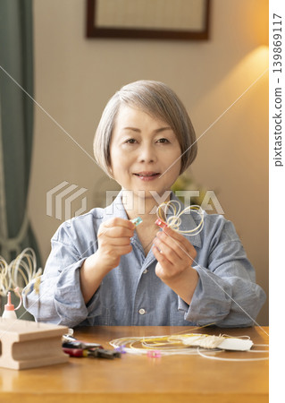 一位老年婦女用水引繩製作髮飾 139869117
