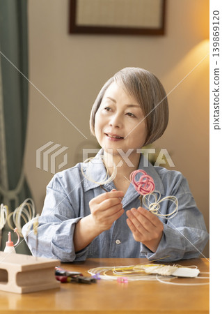 一位老年婦女用水引繩製作髮飾 139869120