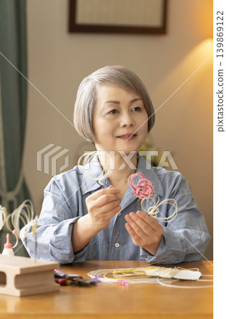 一位老年婦女用水引繩製作髮飾 139869122