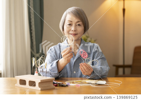 一位老年婦女用水引繩製作髮飾 139869125
