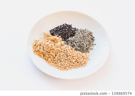Four types of sesame seeds arranged on a white plate 139869574