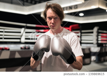 Determined Boxer in Boxing Gloves Posing Inside Ring Determined Boxer in Boxing Gloves Posing Inside Ring 139869615