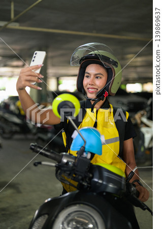 Female Delivery Courier Taking Selfie on Scooter in Garage Female Delivery Courier Taking Selfie on Scooter in Garage 139869637